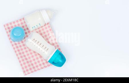 Biberon di formula per bambini con polvere e succhietto su sfondo bianco. Flaconi con tappi blu Foto Stock