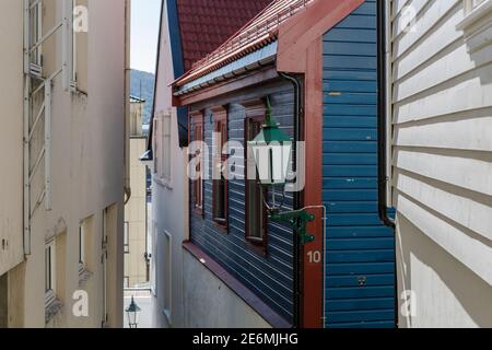 Strada stretta con case con rivestimenti tipici e una vecchia lampada di strada nel centro storico di Bergen, Norvegia Foto Stock