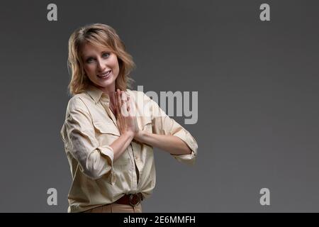 Bella ragazza tiene le sue palme sono piegate di fronte al suo petto per la preghiera su uno sfondo grigio. Meditazione. Concetto di fede, spiritualità e relig Foto Stock