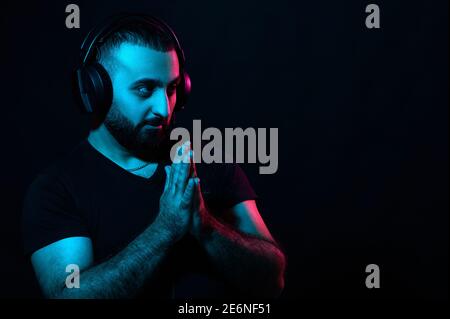 Giovane musicista arabo dj che ascolta la musica con le cuffie su sfondo nero isolato. Giornata internazionale dei DJ Foto Stock