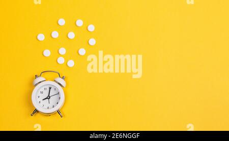 Contraccezione giorno pillole contraccettive con sveglia su sfondo giallo. Foto Stock