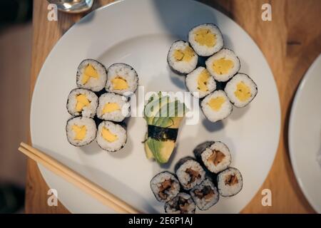 Set di sushi roll, salsa, wasabi e mano con chopsticks su fondo scuro. Vista dall'alto. Disposizione piatta. Cibo giapponese Foto Stock