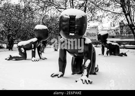 PRAGA, REPUBBLICA CECA - 14 GENNAIO 2021: Bambini - sculture in bronzo installate sull'isola di Kampa a Praga, Repubblica Ceca. Artista: David Cerny. Sculture coperte di neve in inverno. Immagine in bianco e nero. Foto Stock