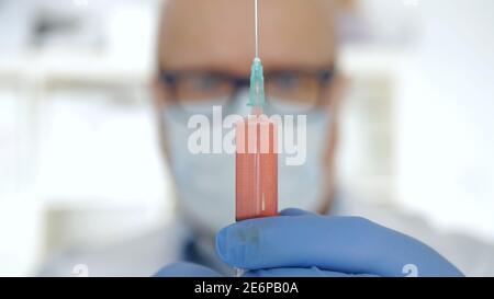 Medico in un ospedale che usa una siringa per fare un vaccino contro le malattie di Coronavirus. Foto Stock