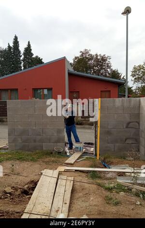 Master sul cantiere, costruzione di una recinzione su un territorio privato, recinzione in calcestruzzo.2020 Foto Stock