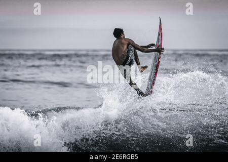 Spiaggia di Copacabana, Rio de Janeiro, Brasile - Aprile 16 2019 - uomo che naviga le onde sulla spiaggia di Copacabana al tramonto Foto Stock