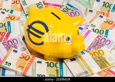 Una banca di porcellini e un mucchio di banconote in euro Foto Stock