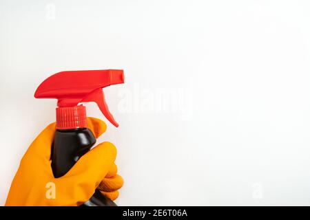 Concetto di pulizia, pulizia e prodotti chimici per la casa. Spray detergente nero in mano in guanto arancione su sfondo bianco. Foto Stock