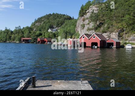 Boathouses rosso e una pista per barche al porto di Il bellissimo villaggio di pescatori Svenevig nel sud della Norvegia Foto Stock