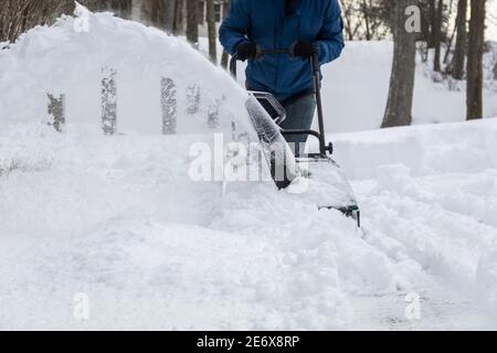 Spazzaneve in azione che disinnevano un vialetto residenziale dopo la neve tempesta Foto Stock