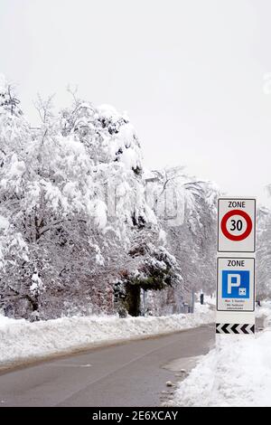 Strada invernale con indicazioni stradali per 30 km limite di velocità e cartello per il parcheggio, che dice in tedesco parcheggio è consentito fino a 5 ore o illimitato. Foto Stock