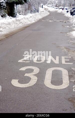 Zona 30 km all'ora velocità ridotta nel villaggio di Urdorf in Svizzera in inverno. Su entrambi i lati della strada ci sono un mucchio di neve. Foto Stock