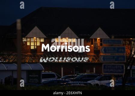 Morrisons shopping superstore silhouette notte girato con segno illuminato su riflettendo su finestre di vetro illuminate e riponi aperto tardi di sera Foto Stock