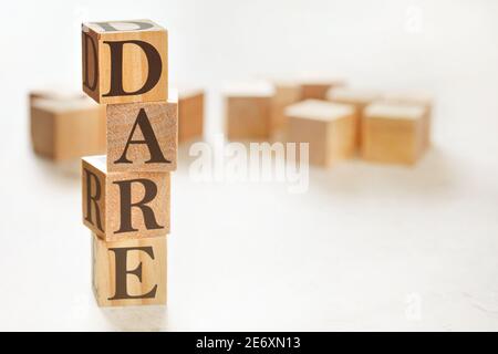 Quattro cubi di legno disposti in pila con il testo DARE (che significa definire, valutare, rispondere, valutare) su di essi, spazio per il testo / immagine in basso a destra angolo Foto Stock