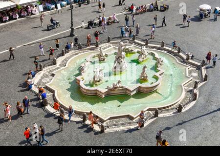 Guardando verso il basso sulle caffetterie lungo la strada e i turisti a fianco della fontana di Nettuno su una mattina di occupato all'interno della Piazza Navona in Roma, Italia. Foto Stock
