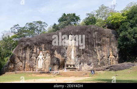 Buduruwagala sculture di roccia piena vista del paesaggio da una distanza, bella e luminosa giornata di sole, antico tempio buddista a Wellawaya, consistono di sette stat Foto Stock