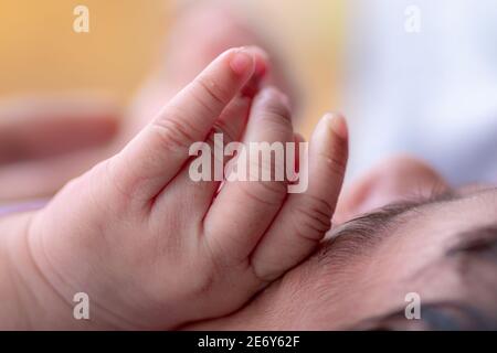 Tre settimane di età adorabile bambino mano sulla sua faccia, dormire cute piccolo Sri Lanka bambino vicino mano e dita. Foto Stock