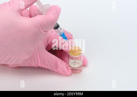 Vaccinazione della popolazione. Un medico che indossa guanti medici raccoglie il vaccino in una siringa monouso. Foto Stock