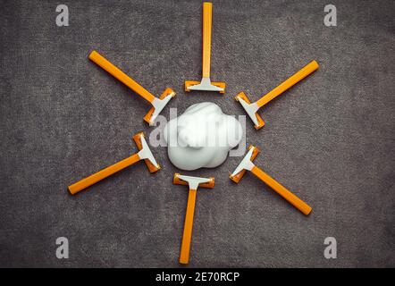 Rasoi monouso arancioni come crema solare e schiuma da barba a forma di nuvola su sfondo grigio, igiene personale, epilazione Foto Stock