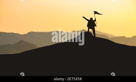 Concetto di successo, Silhouette di imprenditore che detiene una bandiera di vittoria sulla cima della collina Foto Stock