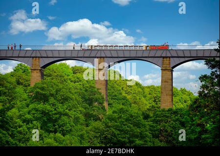 Una chiatta di canale e camminatori attraversano l'acquedotto di Pontcysyllte, parte del canale di Llangollen nel Galles del Nord. È un sito patrimonio dell'umanità dell'UNESCO Foto Stock