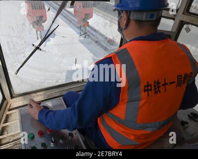 (210130) -- PUTIAN, 30 gennaio 2021 (Xinhua) -- Wang Ruifeng gestisce una gru di trasporto per sollevare una trave in un campo di costruzione della China Railway 11 Bureau Group Co., Ltd. Nella città di Putian, nella provincia di Fujian della Cina sudorientale, 29 gennaio 2021. Wang Ruifeng, nato nel 1997, lavora come operatore di gru da due anni. Lavorando in alto al di sopra del suolo, Wang deve collaborare con i lavoratori a terra per sollevare e spostare travi scatolato di peso superiore a 900 tonnellate esattamente nella posizione specificata. Gli operatori di gru a trave sono diventati indispensabili per la costruzione di ferrovie ad alta velocità. (Xinhua/Song Weiwei Foto Stock