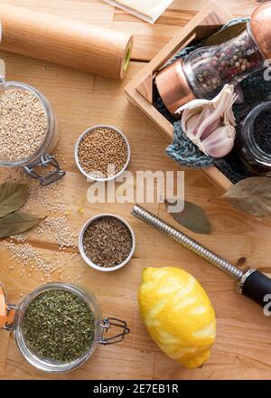 Vista dall'alto di alcuni vasi trasparenti pieni di diversi semi di spezie come sesamo, origano, senape e caraway. Un limone grattugiato è accanto a loro. Foto Stock