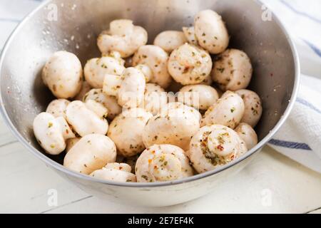 Funghi champignon crudi in una ciotola su fondo bianco rustico preparato per la cottura. Foto Stock