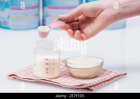 Preparazione della miscela di alimentazione bambino su sfondo marmo in  cucina la mattina con la luce del sole dalla finestra. Biberon con acqua e  latte per neonati formula con il cucchiaio sul