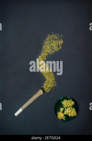 Congiunto con fumo fatto di marijuana e papille di cannabis su sfondo nero con copy space top. Background concettuale di marijuana. Foto Stock