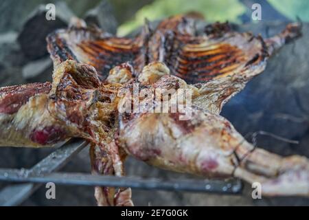 Barbecue rustico di agnello sul fuoco aperto in Patagonia, Argentina, Sud America. L'asado è un traditon di Gaucho con cucina a fiamma libera Foto Stock