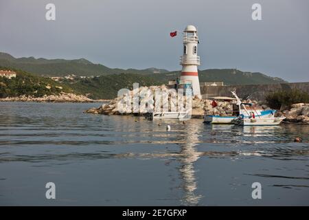 Faro con bandiera turca all'ingresso di un porto, città di Kas, Turchia Foto Stock