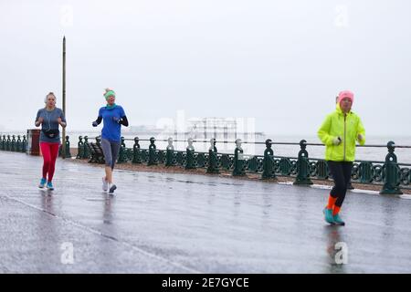 Hove, East Sussex, Regno Unito. 30 Jan 2021. Tempo nel Regno Unito: Una giornata piovosa sul lungomare, mentre la gente fa passeggiate e ogni giorno gli esercizi consentiti tra Hove e la città principale di Brighton. Joggers in giubbotti colorati correre passato. Photo Credit: Paul Lawrenson/Alamy Live News Foto Stock