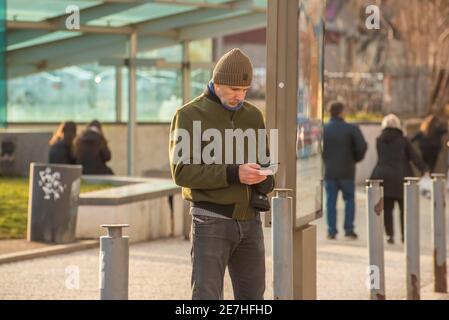 Praga, Repubblica Ceca. 01-29-2021. Ritratto dell'uomo che guarda il suo cellulare nel centro di Praga durante una soleggiata e fredda mattina d'inverno. Foto Stock