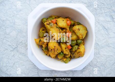 Fuoco selettivo del ribes indiano del piatto laterale Aloo mattar ki sabzi, curry popolare fatto di patate e piselli verdi su fondo bianco Foto Stock