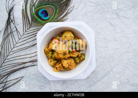 Fuoco selettivo del ribes indiano del piatto laterale Aloo mattar ki sabzi, curry popolare fatto di patate e piselli verdi su fondo bianco Foto Stock