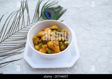 Fuoco selettivo del ribes indiano del piatto laterale Aloo mattar ki sabzi, curry popolare fatto di patate e piselli verdi su fondo bianco Foto Stock