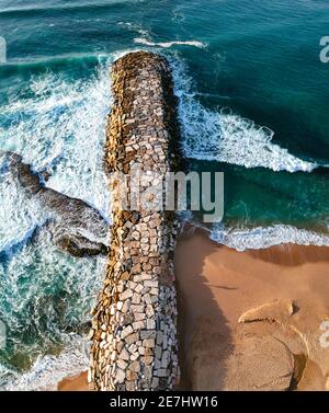 Vista aerea da un molo di pietra. Blocchi di demolitori a onda di pietra per proteggere la costa dall'erosione Foto Stock