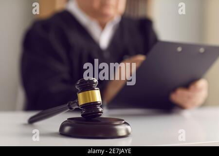 Primo piano di un giuello del giudice sul tavolo sullo sfondo di un giudice che legge il verdetto. Foto Stock