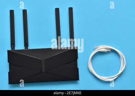 Moderno router wi-fi e cavo ethernet per la connessione a un sfondo blu Foto Stock