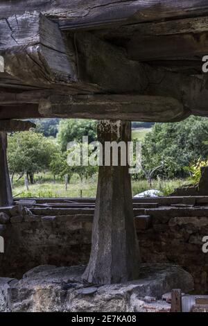 Immagine verticale di un grande megalito verticale che supporta un vecchio casa di legno Foto Stock