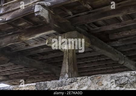 Grande megalito verticale che sostiene una vecchia casa di legno Foto Stock