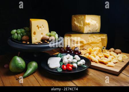 Composizione diversi tipi di formaggio con noci e uva su fondo rustico in legno. Foto Stock