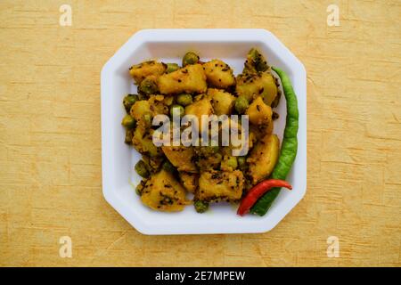 Fuoco selettivo del ribes indiano del piatto laterale Aloo mattar ki sabzi, curry popolare fatto di patate e piselli verdi su fondo bianco Foto Stock