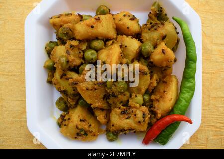 Fuoco selettivo del ribes indiano del piatto laterale Aloo mattar ki sabzi, curry popolare fatto di patate e piselli verdi su fondo bianco Foto Stock