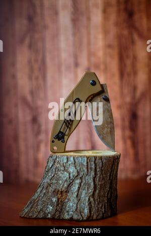 coltello da caccia pieghevole su legno su sfondo marrone Foto Stock