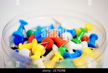 Un mucchio di spille colorate per l'ufficio su sfondo bianco. Foto Stock