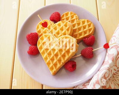 Waffle belgi a forma di cuore con lamponi. Lo sfondo di San Valentino. Foto Stock