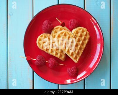 Waffle belgi a forma di cuore con lamponi. Lo sfondo di San Valentino. Foto Stock