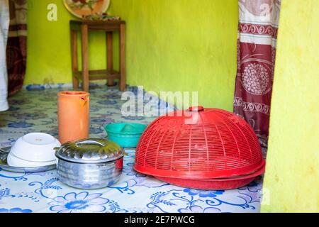 Piatti africani cucinati e serviti in piatti colorati. Interno della modesta vintage stile povera cucina, preparato pasto posato a terra. Vita reale Foto Stock